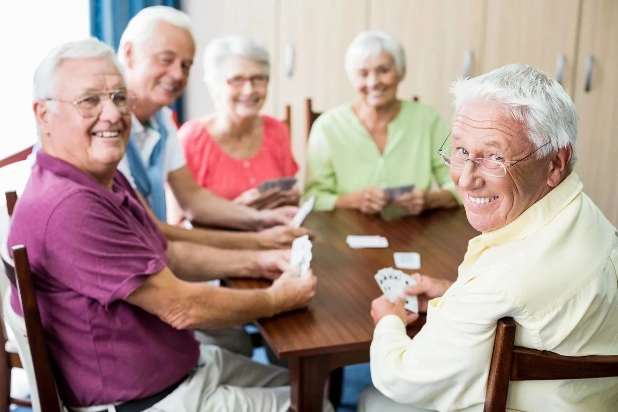 A group of people sitting at a table playing cards.